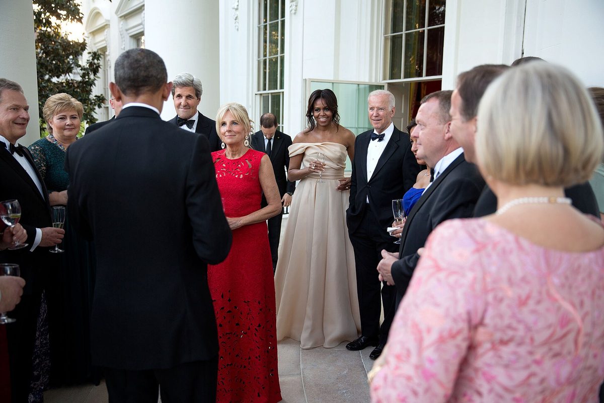 Guests in formal evening wear, including floor-length gowns and tuxedos, gathered at a White House state dinner — illustrating the level of formality this dress code calls for